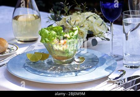 Salade de fruits de mer dans un bol en verre cristal dans un cadre formel de table à l'extérieur - Banque D'Images