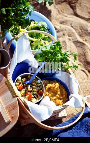 Pique-nique sur la plage avec salades dans des bols et des paniers - Banque D'Images