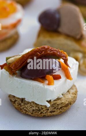 Canape de fromage de chèvre avec olive avec deux feuilles et tomates séchées sur la route ronde - Banque D'Images