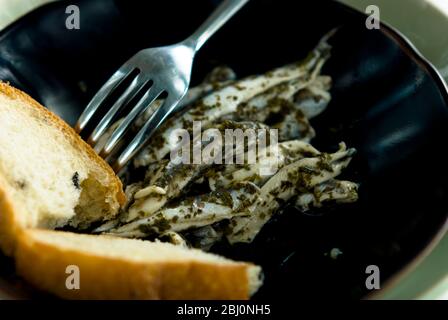 Anchois italiens marinés avec pain sur plaque de poterie noire - Banque D'Images