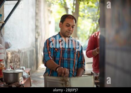 Homme commun cuisine à son stand de bord de route. Banque D'Images