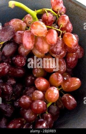 Bouquet de raisins rouges sans semis sur plaque noire - Banque D'Images
