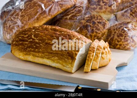 Pain tigre en tranches sur planche en bois avec pain plus emballé derrière - Banque D'Images