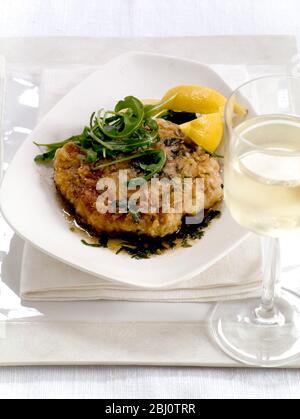 Schnitzel de porc, poêlé avec un revêtement d'oeuf et de farine assaisonnée, avec sauge et citron, servi avec salade de roquette, - Banque D'Images