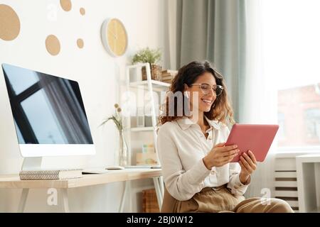 Jeune femme séduisante prenant part à la conférence en ligne tout en restant à la maison pendant les jours de quarantaine Banque D'Images