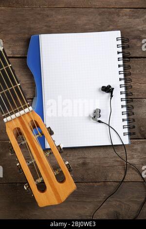 Scène d'enregistrement de musique avec guitare, bloc-notes et écouteurs sur fond en bois Banque D'Images
