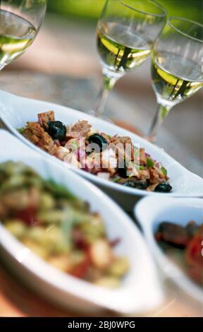 Repas d'été de style tapas dans le jardin français avec petits plats de diverses salades, dont le thon aux olives noires, l'oignon rouge et les herbes à la gl Banque D'Images