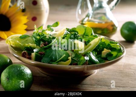 Salade mixte de diverses feuilles, y compris la cresson, la laitue agneaux, la romaine, avec avocat et noix hachées et noisettes avec vinaigrette en bouteille de Banque D'Images