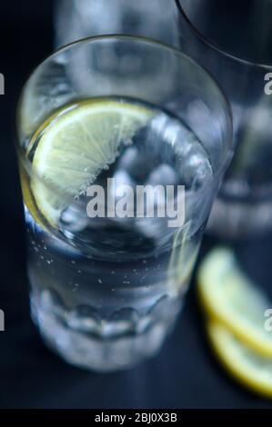 Verre de Pellegrino légèrement pétillant, eau minérale italienne, petit coin de citron sur plateau sombre - Banque D'Images