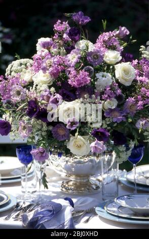 Superbe aménagement de fleurs bleues et blanches au milieu d'une table formelle organisée à l'extérieur dans le jardin d'été - Banque D'Images