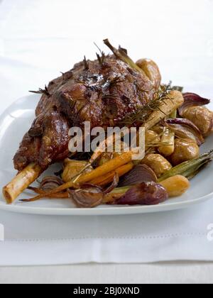 Gigot d'agneau dans la rôtissoire avec de nouvelles pommes de terre rôties dans leurs peaux. - Banque D'Images