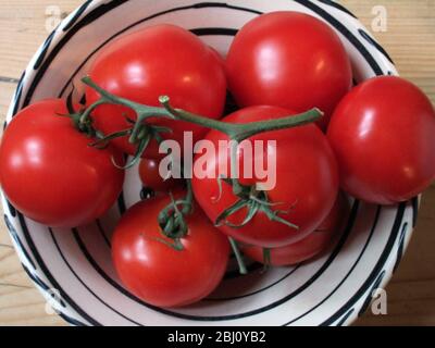Grandes tomates rouges sur la vigne dans un bol en céramique noir et blanc - Banque D'Images