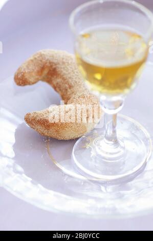 Biscuit en forme de croissant avec verre de vin de dessert sur la plaque de verre - Banque D'Images