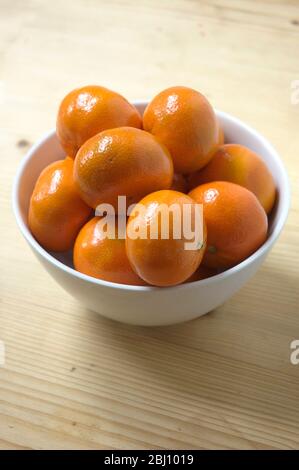 Satsumas dans un bol blanc sur table en bois - Banque D'Images