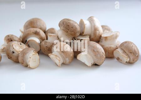 Petits champignons crimini sur planche à découper blanche - Banque D'Images