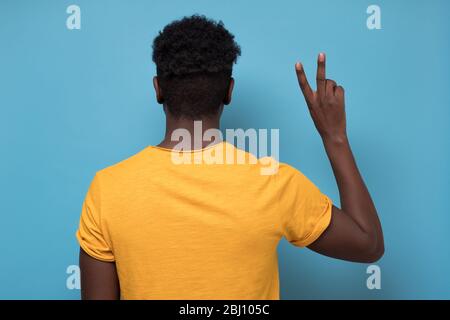 L'homme afro-américain montrant deux doigts de ciseaux mouvement tournant en arrière Banque D'Images