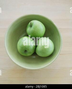 Trois pommes vertes Granny Smith dans un bol en poterie verte Banque D'Images