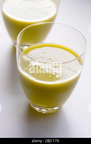 Fruits kiwi fraîchement juiissés et orange dans deux verres sur fond blanc - Banque D'Images