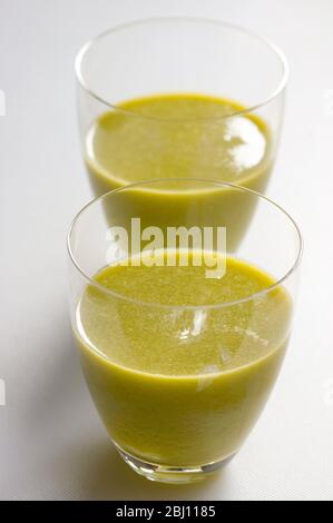 Fruits kiwi fraîchement juiissés et orange dans deux verres sur fond blanc - Banque D'Images