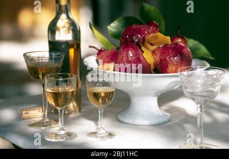 Poires au vin rouge servies à l'extérieur au soleil de printemps français avec vin de dessert - Banque D'Images