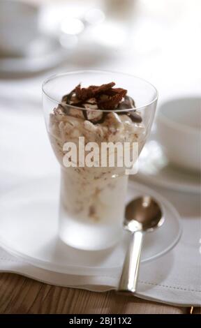 Dessert au chocolat et à la crème dans un verre moderne sur une petite assiette en verre dans un cadre de table - Banque D'Images