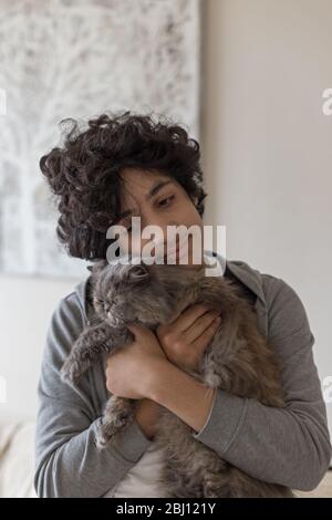 Portrait d'un adolescent tenant un chat persan Banque D'Images