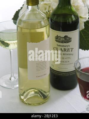 Bouteilles et verres de vin rouge et blanc avec des fleurs d'hydracea derrière - - Banque D'Images