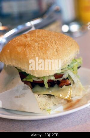 Hamburger BLT dans un pain de sésame dans un sac en papier sur une plaque blanche au comptoir d'un restaurant de style américain classique - Banque D'Images