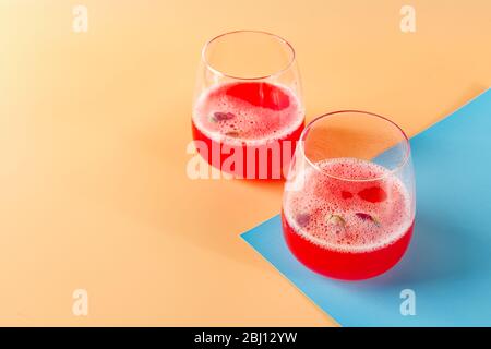 Cocktail alcoolique rose avec limonade, champagne ou Martini décoré de boutons secs sur fond coloré Banque D'Images