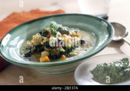 Soupe de minestrone dans un bol vert, avec pesto - Banque D'Images