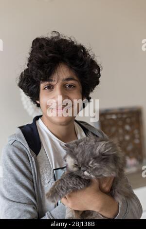 Portrait d'un adolescent tenant un chat persan Banque D'Images