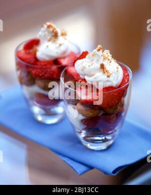 Dessert d'été de biscuits de ratafia avec fraises fraîches, coupées en deux et crème fouettée avec garniture de noix hachée - Banque D'Images
