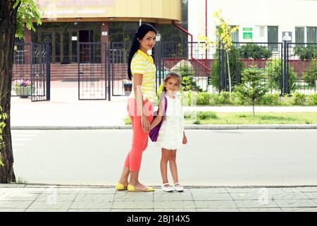 Belle petite fille avec la mère près de l'école Banque D'Images