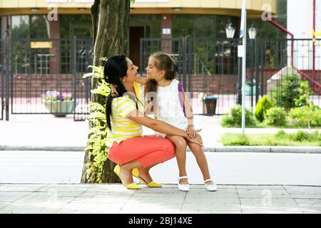 Belle petite fille avec la mère près de l'école Banque D'Images