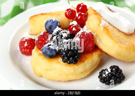 Beignets de fromage cottage avec baies en assiette, fermeture Banque D'Images