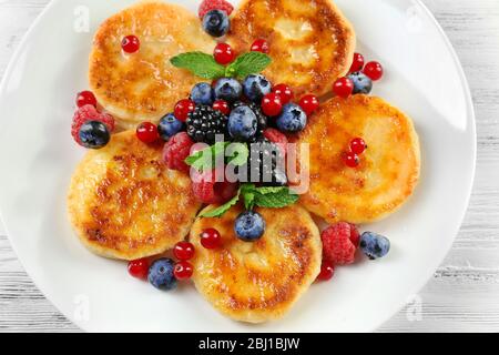 Beignets de fromage cottage avec baies en plaque sur table en bois, ferme Banque D'Images