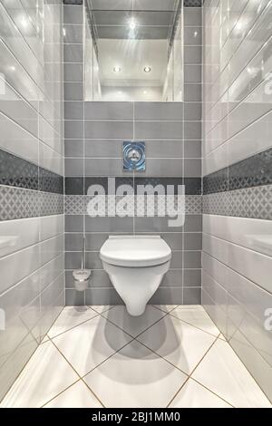 Cuvette de toilette montée en blanc dans la salle de bains moderne avec miroir et brosse de toilette Banque D'Images