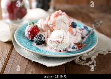 Délicieuse glace aux baies fraîches et à la sauce congelées, sur fond en bois Banque D'Images