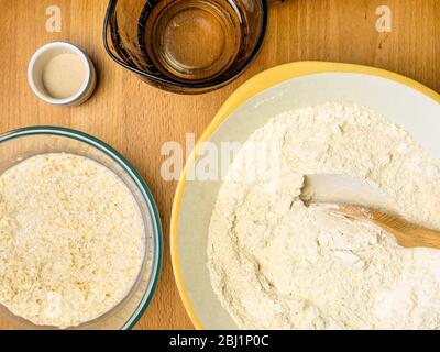 Mélanger la farine d'avoine avec la farine de pain blanc forte tout en trempant l'avoine dans le lait d'avoine avec la levure et l'eau pour faire du pain d'avoine Banque D'Images