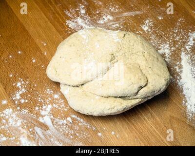 Pâte à pain d'avoine sur une table de cuisine farinée prête à pétrir Banque D'Images