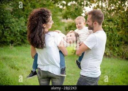 Portrait de famille avec deux enfants debout dans un pré, souriant et envieux. Banque D'Images