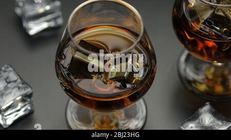 Whisky doré, cognac ou brandy dans des verres avec glaçons sur la surface noire. Vue rapprochée des verres avec alcool, bourbon, rhum Banque D'Images