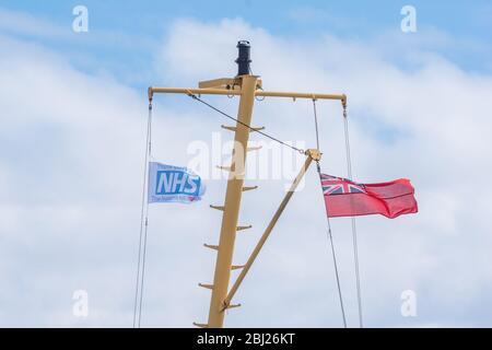 NHS, le drapeau des héros de remerciement, avec panneau rouge endévolant sur mât sur le seigneur de ferry Calmac des îles dans les Hébrides extérieures de l'Uist du Sud, Ecosse Banque D'Images