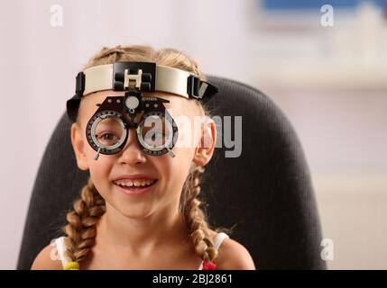 Jeune fille en cours de test oculaire avec le phoropter sur fond flou Banque D'Images