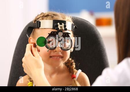 Jeune fille en cours de test oculaire avec des lunettes sur fond flou Banque D'Images