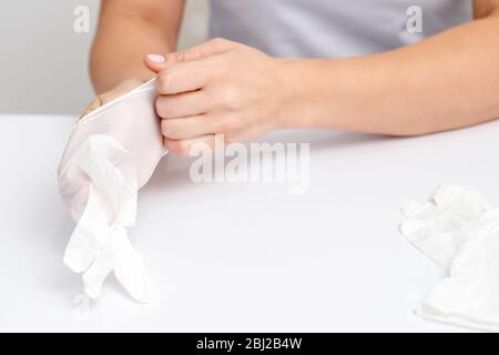 Les mains des femmes mettent les gants en caoutchouc blanc dans un salon de manucure. Banque D'Images