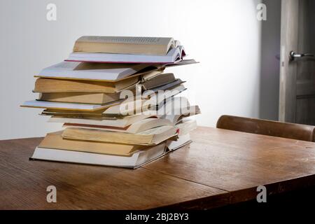 de nombreuses piles de livres éducatifs ouverts pour la préparation de l'apprentissage pour les examens d'université sur une table en bois sur un fond blanc. Auto-éducation. educ en ligne Banque D'Images