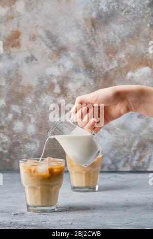 Verser la crème à la main dans du café glacé dans le verre de roches Banque D'Images