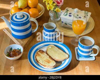 Table de cuisine en bois avec service de cornishware avec pain grillé et une tasse de thé Banque D'Images