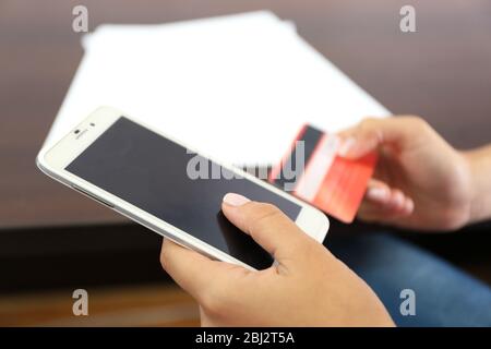 Femme vérifie le solde du compte sur smartphone avec l'application bancaire mobile sur fond de table en bois Banque D'Images